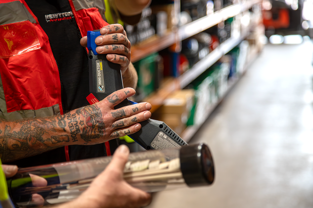Person holding a tool in a warehouse setting